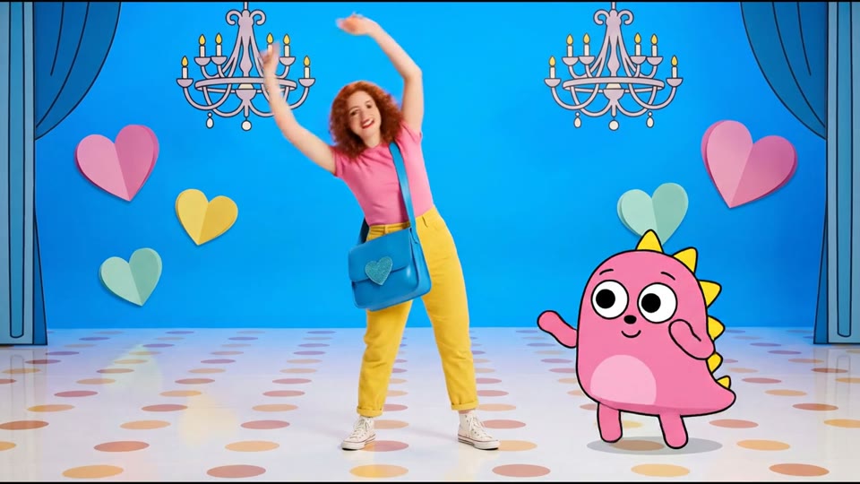 A dancer and pink animated character in a colourful set