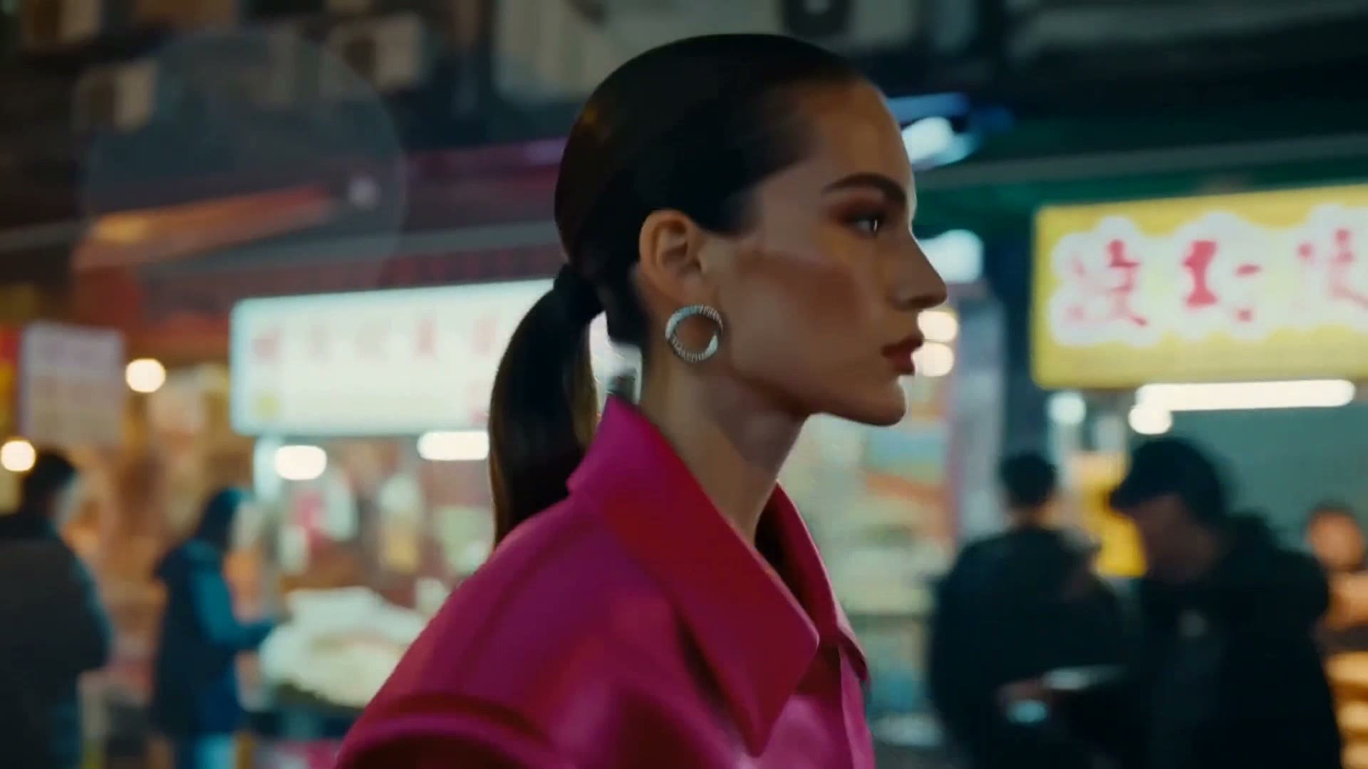 A woman in a vivid pink jacket moves through a neon-lit night market and into a rain-streaked car.