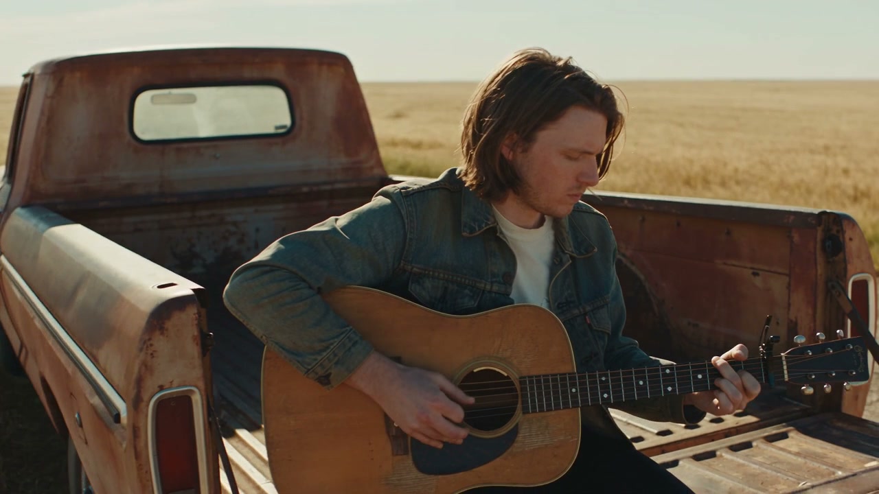 An acoustic performance in a pickup truck, surrounded by open fields and afternoon light.