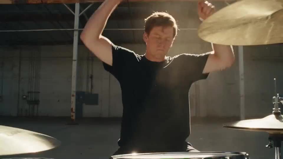 A drummer in a sunlit rehearsal space